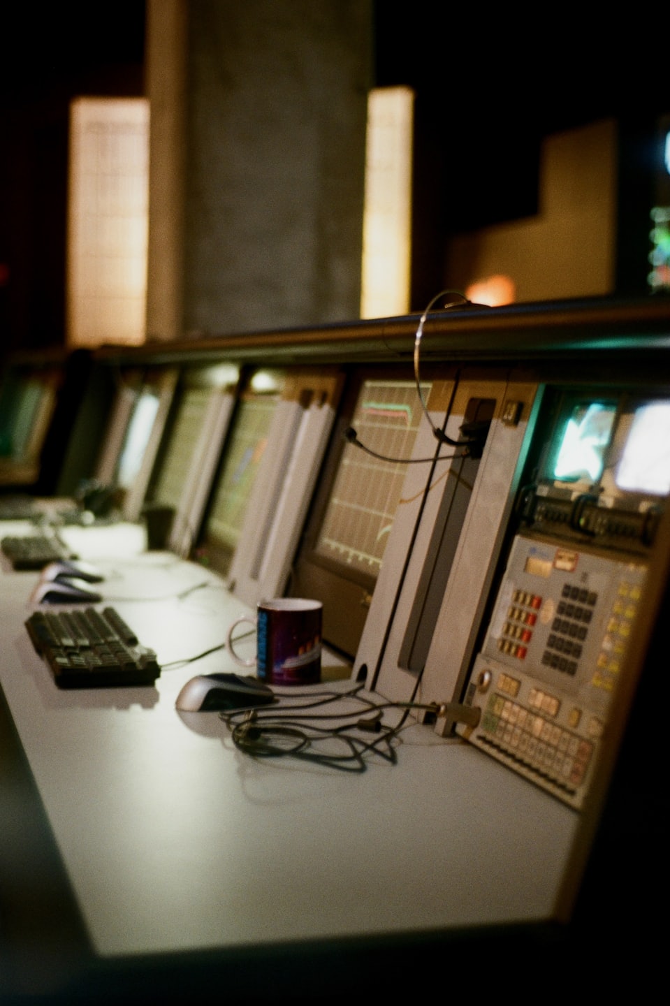 Control room console with monitors and a coffee mug.
