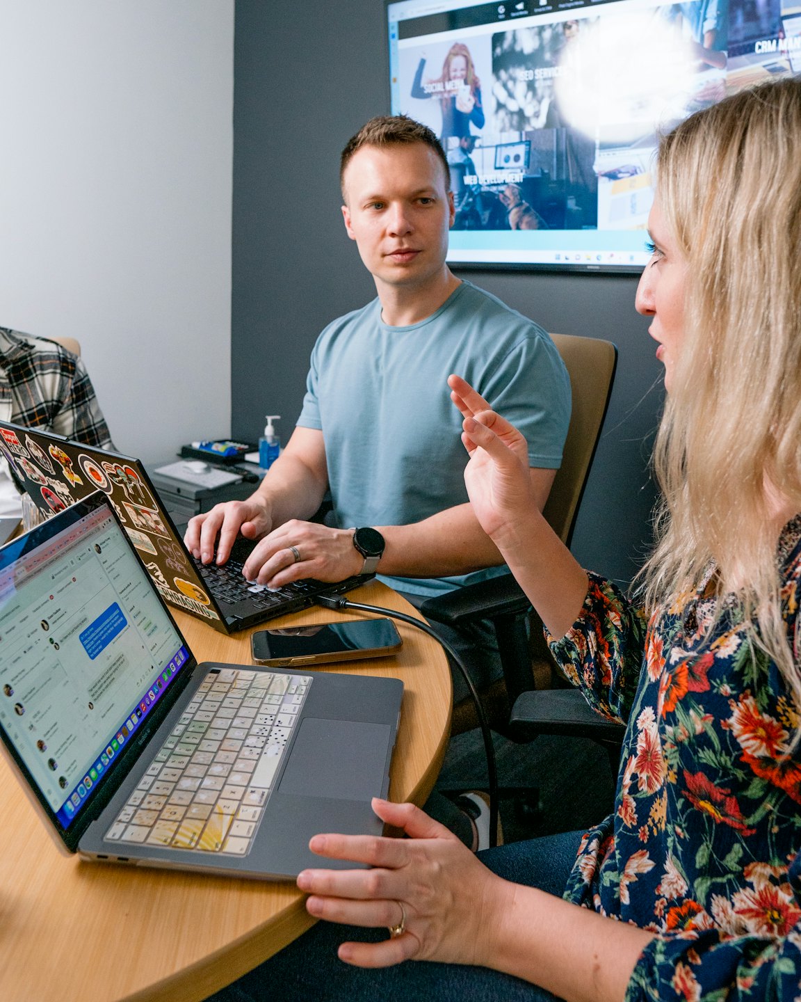 Colleagues discuss digital services on laptops in a modern office.
