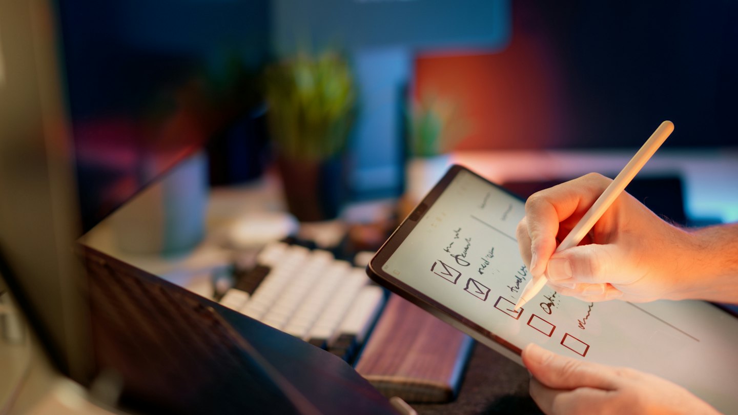 Hands use a stylus to mark items on a digital checklist.
